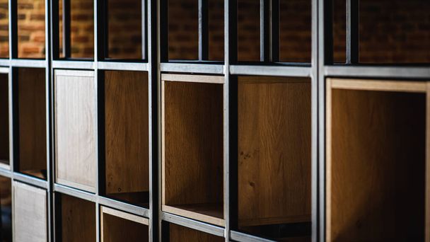 Fragment of light wooden cabinet. Empty cabinet shelves. Wooden shelf in a metal frame with empty racks  - Fotó, kép