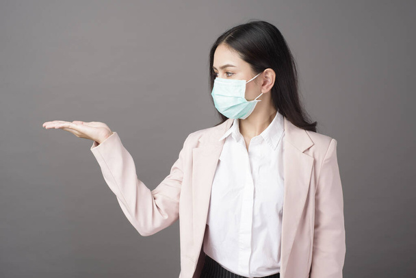 Business woman with mask  is showing something on her hand  - Фото, изображение