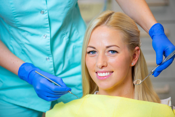 Žena sedí v křesle v zubařské ordinaci na zubní prohlídku - Fotografie, Obrázek