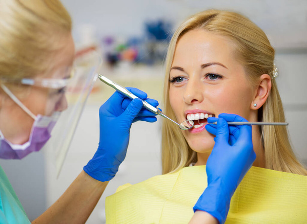 Patientin lässt ihre Zähne vom Zahnarzt untersuchen - Foto, Bild