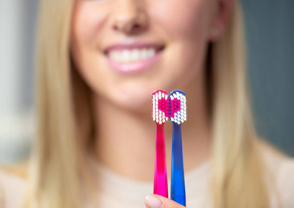 Elinde diş fırçası tutan bir kadın kalp sembolü oluşturuyor. - Fotoğraf, Görsel