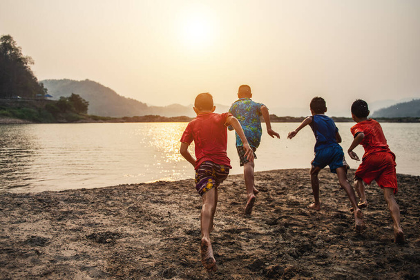 visão traseira de meninos despreocupados correndo na água e se divertindo no lago
 - Foto, Imagem