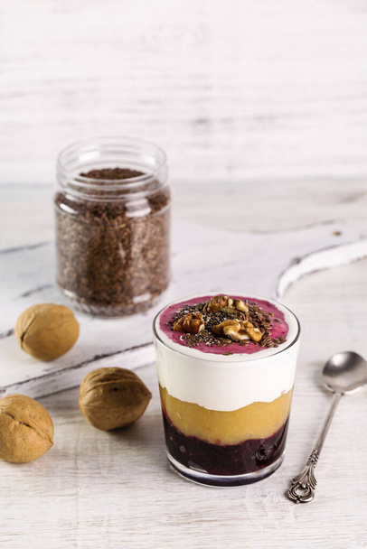 Delicious dessert layer of yogurt with applesauce, currant jam and nuts. Dessert served in a glass with a spoon. - Photo, Image