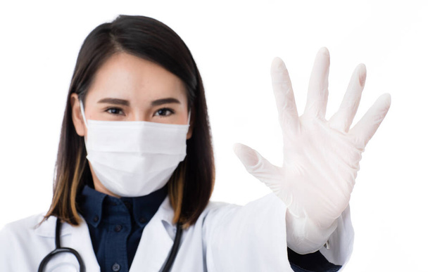 外科衛生保護マスクを身に着けている研究室のコートのドレスで美しいアジアの女性医師は拒否のための信号で手を上げ、否定し、何かを制限します。悪いことを禁止する概念. - 写真・画像