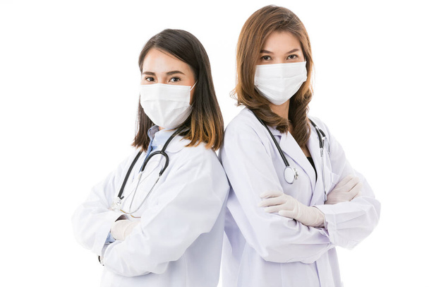 Két női orvos, akik sebészeti védőmaszkot viselnek, fehér alapon állnak elszigetelten, a fénymásolótérrel való csapatmunka pózában. Ötletek az egészségügyi vállalkozások és az egészségügyi dolgozók számára. - Fotó, kép
