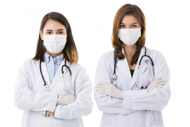 Two female doctors wearing surgical protective hygiene mask standing together isolated on white background in the pose of teamwork with copy space. Idea for health care business and medical people. - Photo, image