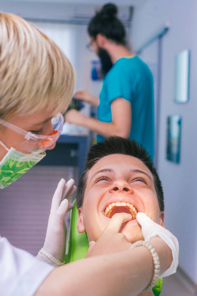Крупный план пациента, показывающего зубную боль женщине-дантисту в стоматологическом кабинете. - Фото, изображение