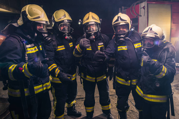 Equipo de bomberos en uniforme con máscaras de gas dentro del departamento de bomberos
 - Foto, Imagen