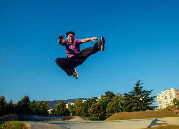 Acrobat practicing parkour exercises at the local skatepark - Photo, Image