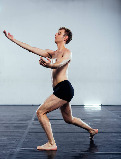Flexible shirtless man performing an artistic dance movement - Photo, Image
