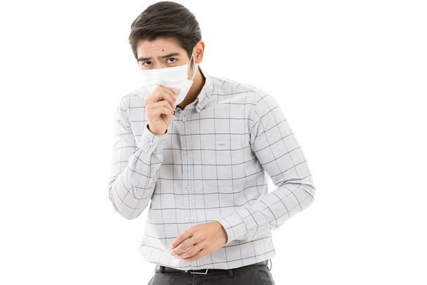 Young and handsome man in casual business cloth wearing medical flu protective mask. Isolated on white background. He is coughing. Concept of health care and protection from dirty air pollution. - Photo, Image