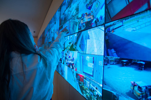 Охоронець стоїть перед великим монітором CCTV у головній контрольній кімнаті під час читання та обговорення планів. - Фото, зображення