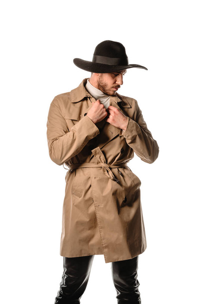 Attractive young stylish man posing in beige long coat and black hat - Fotoğraf, Görsel