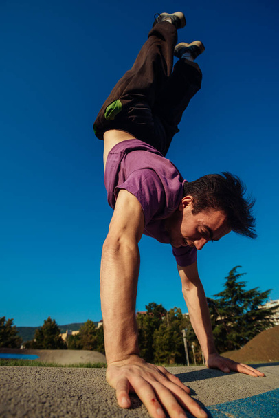 Jovem muscular cara realizando truques de parkour ao ar livre em um parque de skate - Foto, Imagem