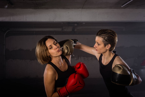 lähikuva kahdesta naisnyrkkeilijästä, joissa on nyrkkeilyä ja nyrkkeilyä suojaava varustus
 - Valokuva, kuva