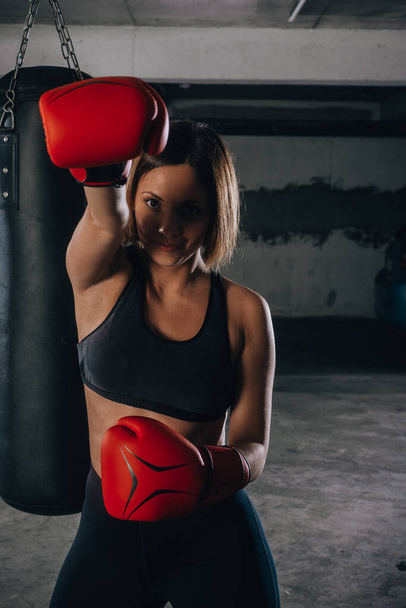 Портрет уверенной молодой женщины в красных боксёрских перчатках и черном спортивном лифчике
 - Фото, изображение