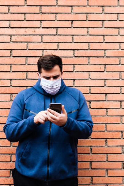 El hombre está tocando su móvil con una máscara médica
. - Foto, Imagen