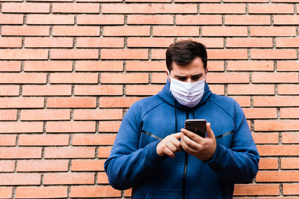 Man is touching his mobile phone with a medical mask. - Foto, Imagem