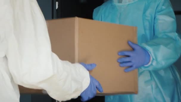 Entrega de equipo médico al hospital. Las personas con trajes protectores entregan cajas - Metraje, vídeo