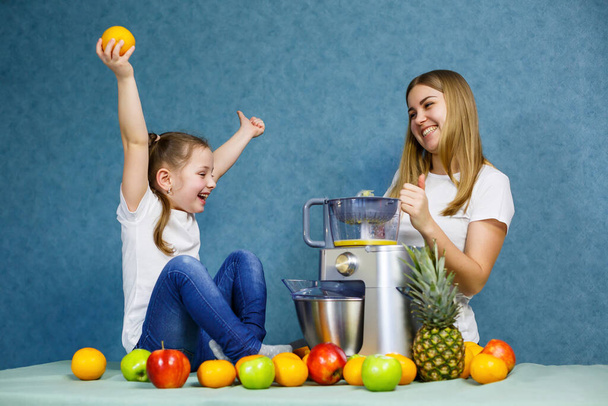 Little girl with mom plays with fruits and smiling. Vitamins and healthy nutrition for children. - Photo, Image