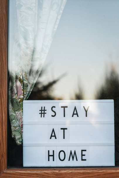 Zůstaňte doma 'slova na dřevěné světelné skříňce, zobrazené v okně, odrážející západ slunce, Bezpečnostní koncepce. # Lockdown Art - Fotografie, Obrázek
