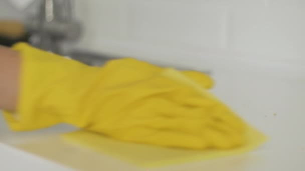 Háziasszony nő sárga kesztyűben tiszta morzsa az asztalon sárga ronggyal - Felvétel, videó