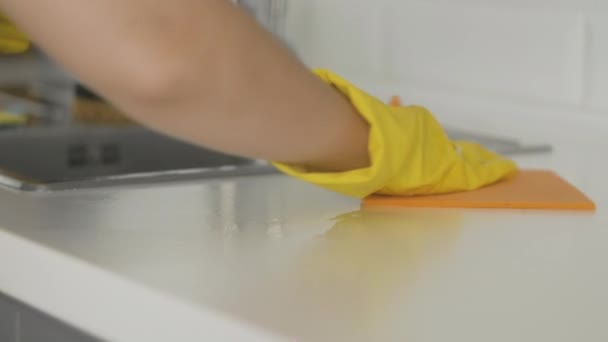 Gospodyni domowa w żółtych rękawiczkach oczyścić stół z szmatą - Materiał filmowy, wideo