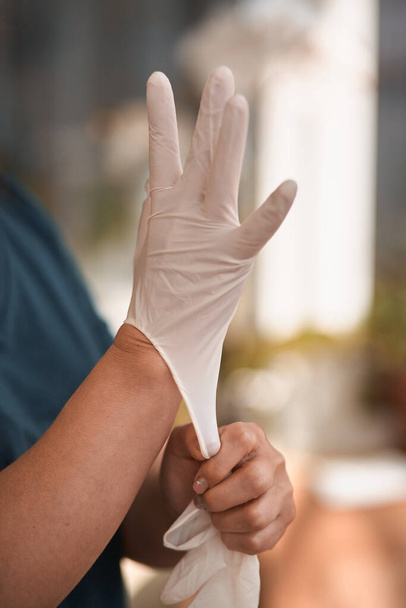 Vrouwelijke chirurg of verpleegkundige die een steriel pak draagt en steriele rubberen handschoenen aantrekt om een operatie uit te voeren, Hand met chirurgische handschoenen voor aanvang van de operatie, Stapsgewijze procedures. - Foto, afbeelding