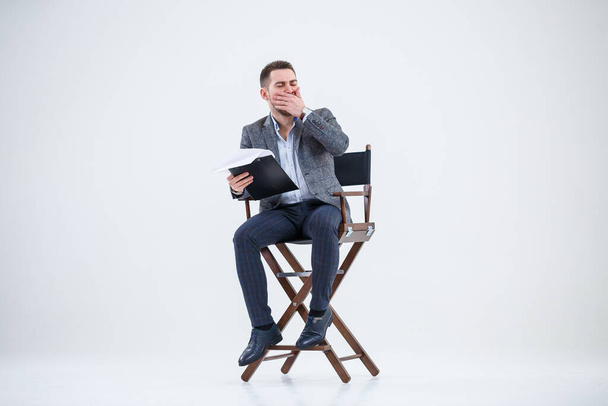 Uomo d'affari uomo d'affari in giacca e cravatta seduto su una sedia di legno e getta documenti. Su uno sfondo bianco con pensieri di un nuovo progetto
 - Foto, immagini