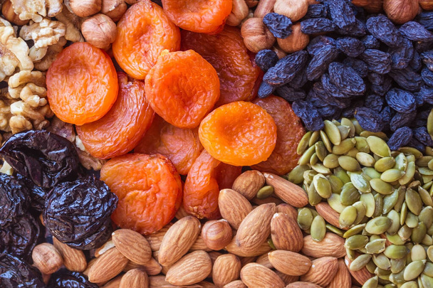 Abundance, useful natural food, nourishing snack. Nuts, dried apricots, raisins, prunes and pumpkin seeds. Sources of vegetable protein. View from above. - Photo, Image