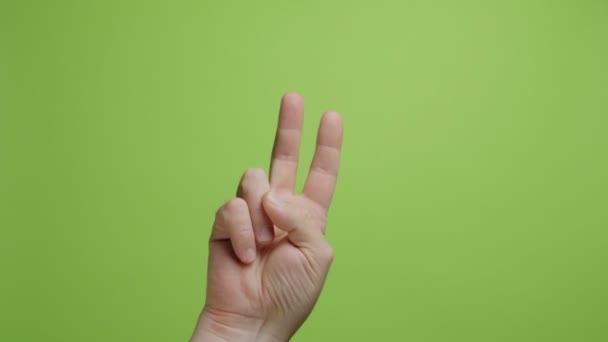 Hands make symbol. Men hands show Peace and victory gesture on green background - Footage, Video
