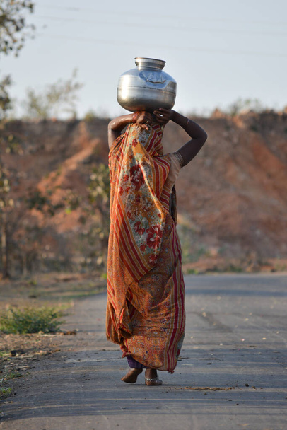 An Indian woman carrying a container of water on her head - Photo, Image