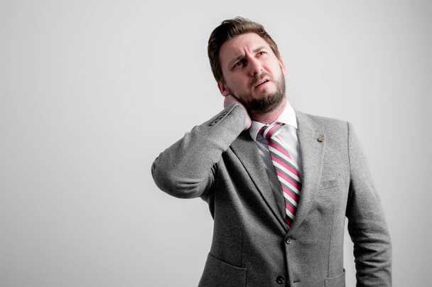 Ritratto di uomo d'affari che indossa abiti da lavoro gesticolando dolore al collo isolato su sfondo grigio con spazio copia pubblicità
 - Foto, immagini
