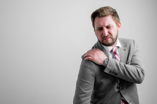 Porträt eines Geschäftsmannes in Businesskleidung gestikuliert Schulterschmerzen isoliert auf grauem Hintergrund mit Kopierraum Werbefläche - Foto, Bild