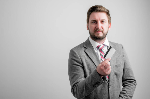 Porträt eines Geschäftsmannes in Businesskleidung, der Carg isoliert auf grauem Hintergrund mit Kopierraum-Werbefläche zeigt - Foto, Bild