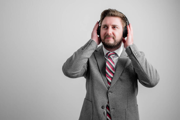Porträt eines Geschäftsmannes in Business-Kleidung hören gute Musik isoliert auf grauem Hintergrund mit Kopierraum Werbefläche - Foto, Bild