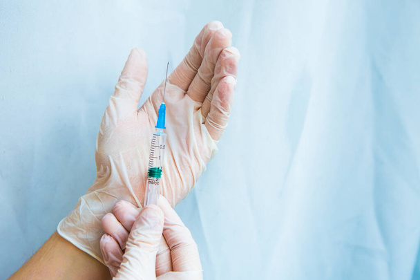 hands in white gloves hold a syringe on a blue background. Coronavirus disinfectants, asian flu outbreak, Coronavirus 2019-nCoV, Corona virus outbreaking. Spray bottle - Fotó, kép