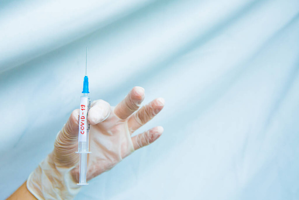 hands in white gloves hold a syringe on a blue background. Coronavirus disinfectants, asian flu outbreak, Coronavirus 2019-nCoV, Corona virus outbreaking. Spray bottle - Fotó, kép