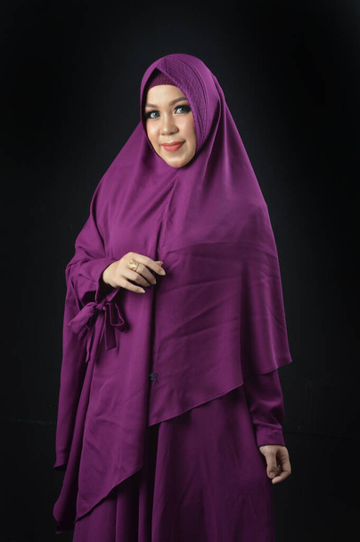portret pięknej muzułmanki w fioletowej chustce na czarnym tle - Zdjęcie, obraz