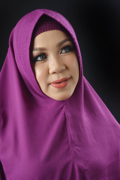 黒の背景に隔離された紫色のスカーフを着た美しいイスラム教徒の女性の肖像画 - 写真・画像