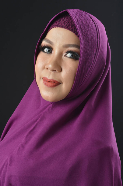 ritratto di una bella donna musulmana con un velo viola isolato su sfondo nero
 - Foto, immagini