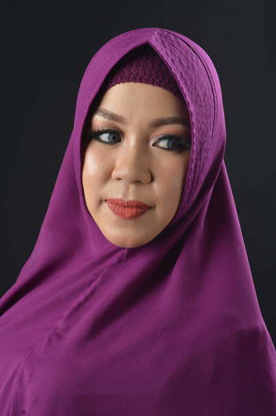 portrait d'une belle femme musulmane portant un foulard violet isolé sur fond noir
 - Photo, image