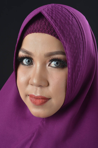 portrait d'une belle femme musulmane portant un foulard violet isolé sur fond noir
 - Photo, image