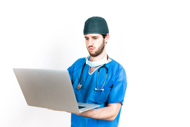 Jonge arts met behulp van laptop poseren geïsoleerd op witte achtergrond - Foto, afbeelding