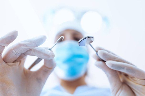 Стоматолог з інструментами над пацієнтом
 - Фото, зображення