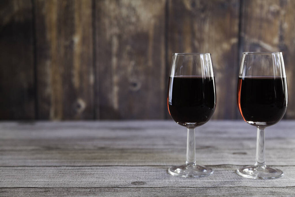  dvě sklenice červené víno na dřevěném stole a dřevěném pozadí. Kopírovat prostor - Fotografie, Obrázek