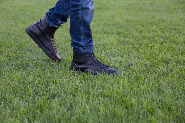 Nahaufnahme männlicher Beine in stylischen Lederschuhen, die durch grünes Gras spazieren - Foto, Bild