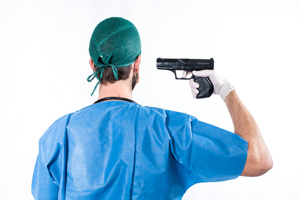 Young doctor holding gun isolated on white background - Foto, Bild