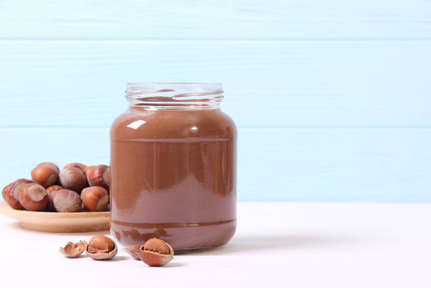 chocolate paste in a glass jar on a colored background. Chocolate butter, chocolate sauce. - Φωτογραφία, εικόνα