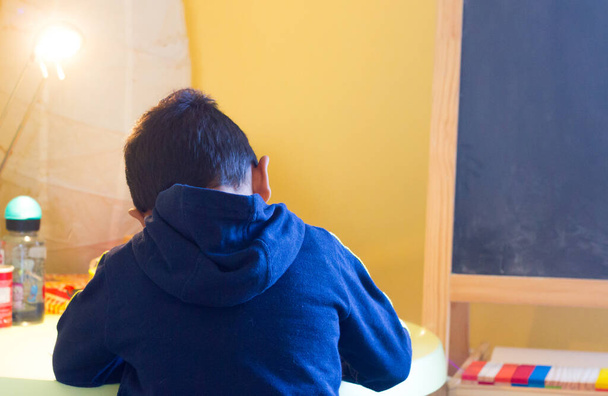 Маленький латиноамериканець робить домашнє завдання. Утилізація під час карантину Ковид-19 - Фото, зображення